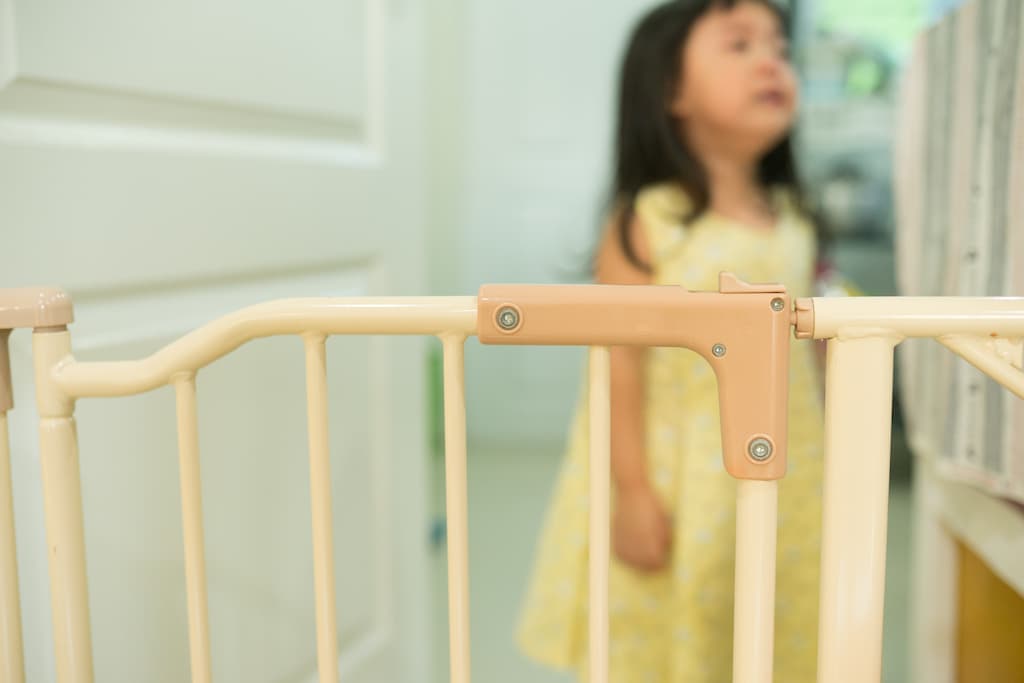 Little girl staying behind the baby gate