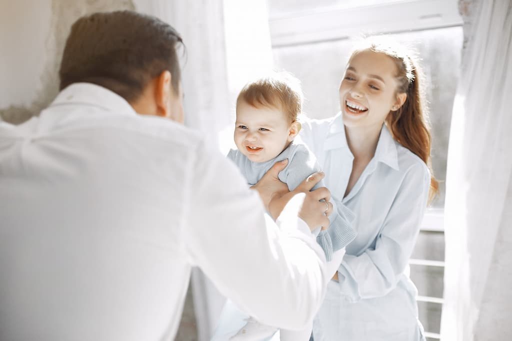 Two dentists holding a baby and laughing